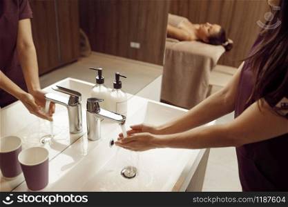 Female masseur washes her hands before massage procedure in spa salon. Massaging and relaxation, body and skin care. Female masseur washes her hands before massage
