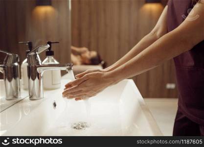 Female masseur washes her hands before massage procedure in spa salon. Massaging and relaxation, body and skin care