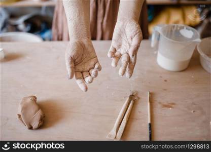 Female master hands covered with dried clay, pottery workshop interior on background. Woman molding a bowl. Handmade ceramic art, tableware making. Female master hands covered with clay, pottery
