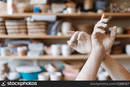 Female master hands covered with dried clay, pottery workshop interior on background. Woman molding a bowl. Handmade ceramic art, tableware making