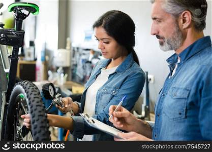 female mechanic checking bicycles tyre presssure