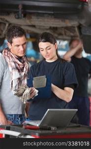 Female mechanic explaining cost to the client standing next to her with person in background