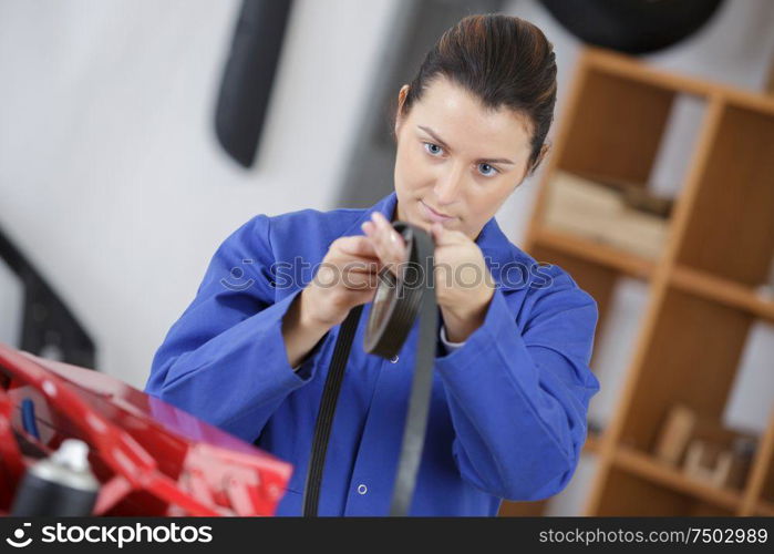 female mechanic holding a car belt