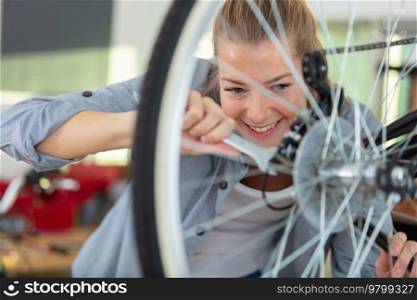female mechanic is repairing bicycle using a spanner
