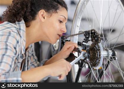 female mechanic tightening pedal on bicycle