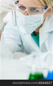 Female medical or research scientist or doctor using looking at a test tube of clear solution in a lab or laboratory