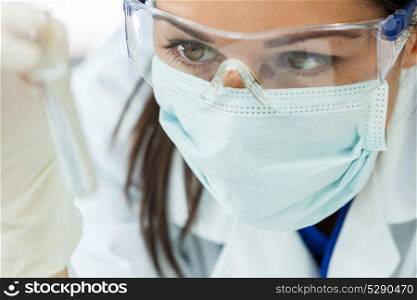 Female medical or research scientist or doctor using looking at a test tube of clear solution in a lab or laboratory
