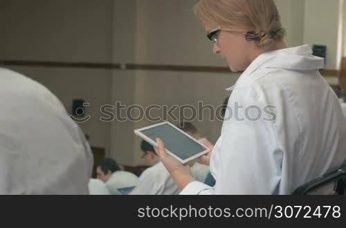 Female medical student or doctor typing on digital tablet in auditorium on the lecture or conference