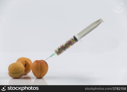 Female menopause and sexual disease metaphor: apricots and syringe with pills meaning cosmetic and health treatment for female ageing