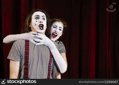 female mime artist grabbing male mime s neck