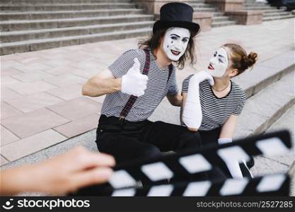 female mime looking male mime gesturing thumbs up