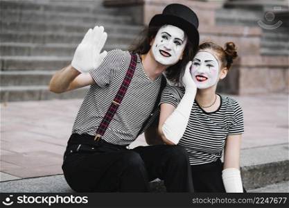 female mime sitting with male mime gesturing goodbye