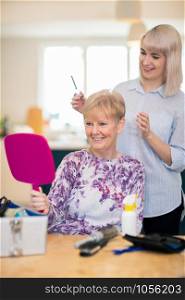 Female Mobile Hairdresser Cutting Senior Womans Hair At Home