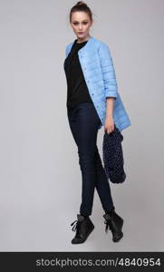 Female model posing in a studio full length. Fashion, jacket, blue. Youth.