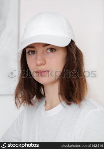 Female model wearing a white baseball cap. White cap mockup, template for picture, text or logo. Girl holding visor of cap. Free space, copy space. Female model wearing a white baseball cap. White cap mockup, template for picture, text or logo. Girl holding visor of cap. Free space, copy space.