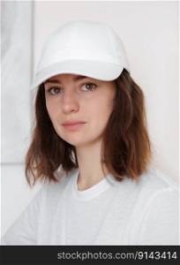 Female model wearing a white baseball cap. White cap mockup, template for picture, text or logo. Girl holding visor of cap. Free space, copy space. Female model wearing a white baseball cap. White cap mockup, template for picture, text or logo. Girl holding visor of cap. Free space, copy space.