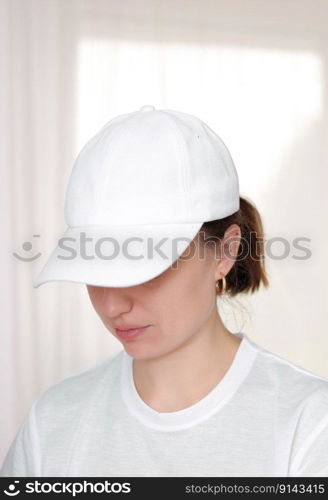 Female model wearing a white baseball cap. White cap mockup, template for picture, text or logo. Girl holding visor of cap. Free space, copy space. Female model wearing a white baseball cap. White cap mockup, template for picture, text or logo. Girl holding visor of cap. Free space, copy space.