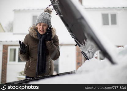 Female Motorist Broken Down In Snow Calling For Roadside Assistance On Mobile Phone
