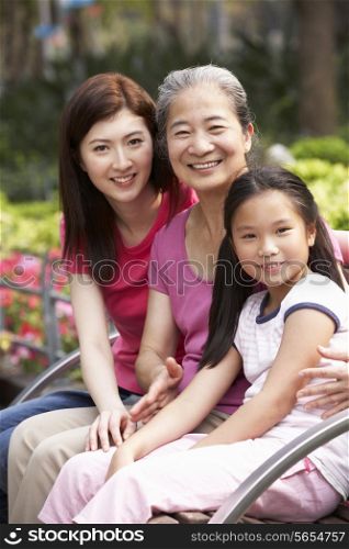 Female Multi Genenration Chinese Family Group Sitting On Bench In Park Together