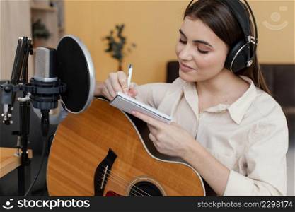 female musician home writing song while playing acoustic guitar