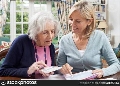 Female Neighbor Helping Senior Woman With Domestic Finances