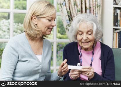 Female Neighbor Helping Senior Woman With Medication