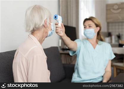 female nurse checking elder woman s temperature
