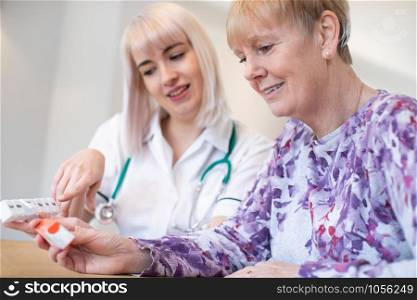 Female Nurse Discussing Medication With Senior Woman Patient