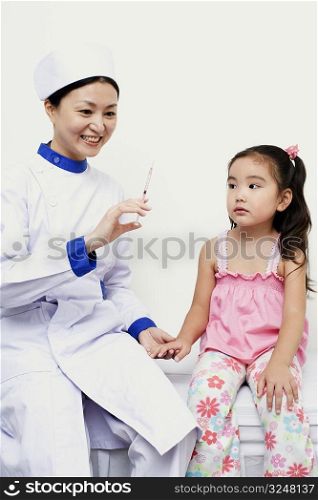 Female nurse holding a girl and a syringe