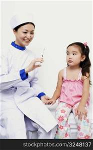 Female nurse holding a girl and a syringe