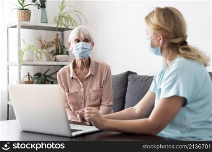 female nurse older woman conversing laptop nursing home