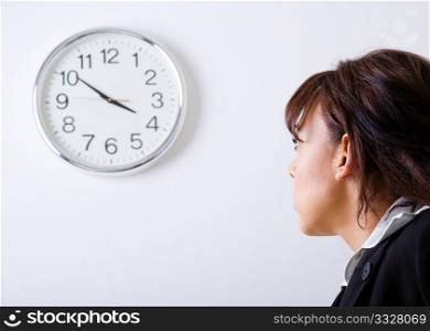 Female office worker looking at a clock on the wall