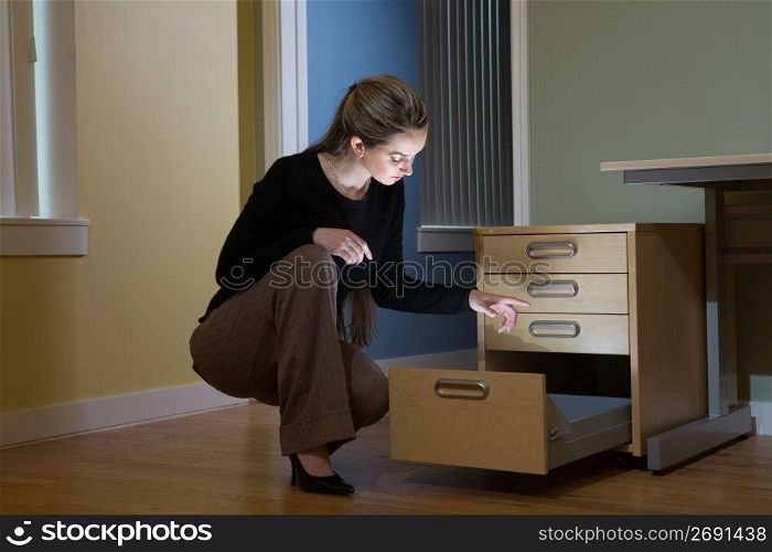 Female office worker looking into illuminated filing cabinet