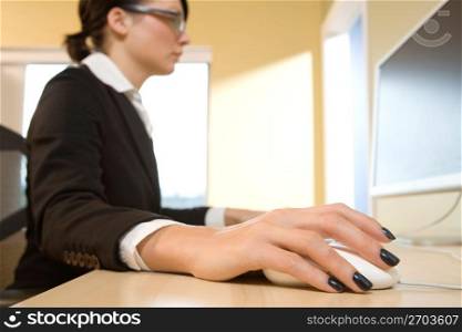 Female office worker sitting at a computer and holding a computer mouse