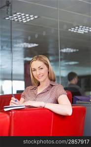 Female office worker sitting on sofa in office portrait