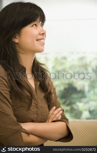 Female office worker standing with her arms crossed and smiling in an office