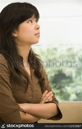 Female office worker standing with her arms crossed and thinking