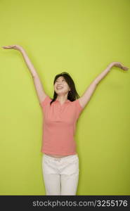 Female office worker standing with her arms raised and smiling