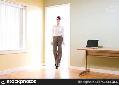 Female office worker walking through office doorway