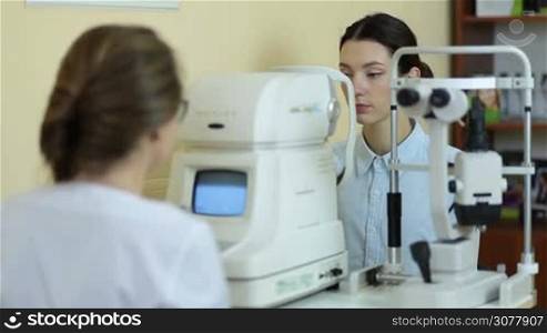 Female ophthalmologist measuring intraocular pressure of young beautiful woman with modern tonometer in ophthalmology clinic. The patient in ophthalmologist&acute;s office during computer vision defects study.