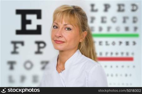 Female optician standing in front of eyesight test at hospital