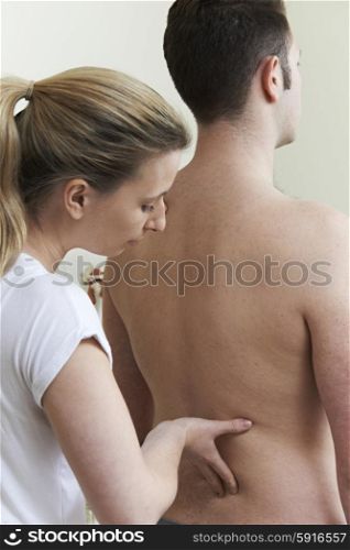 Female Osteopath Treating Male Patient With Back Problem