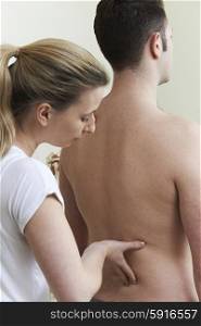 Female Osteopath Treating Male Patient With Back Problem
