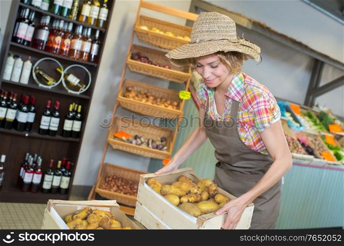 female owner holding various vegetables in crate at greenhouse