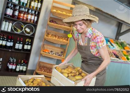 female owner holding various vegetables in crate at greenhouse