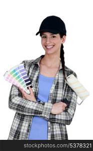 female painter holding a roller brush and a color chart