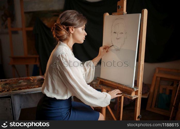 Female painter in studio, pencil sketch on easel. Creative paint, woman drawing portrait, workshop interior on background. Female painter in studio, pencil sketch on easel