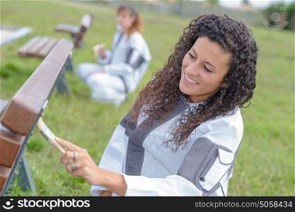 female painter painting the bench