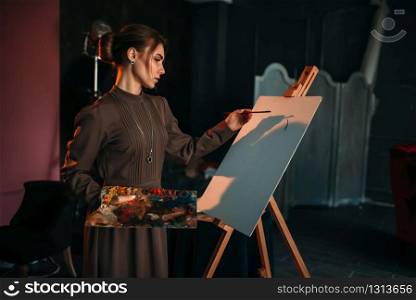 Female painter with brush and palette in hands in art studio. Oil paint, paintbrush drawing. Female painter with brush and palette in hands