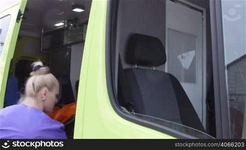 Female paramedic in ambulance talking with dispatcher on radio and driving to destination